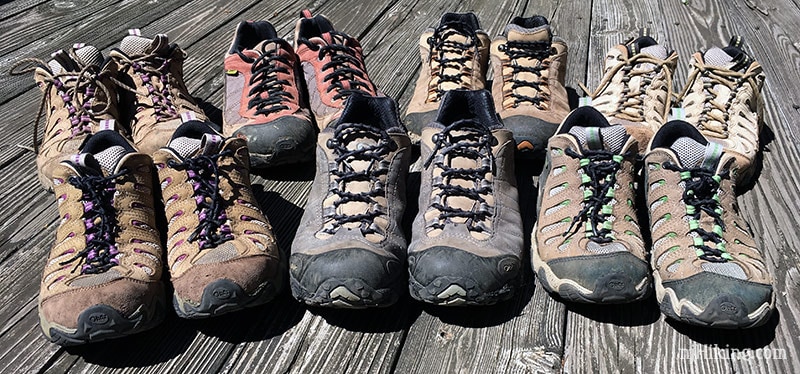 Multiple men and women's hiking shoes lined up.