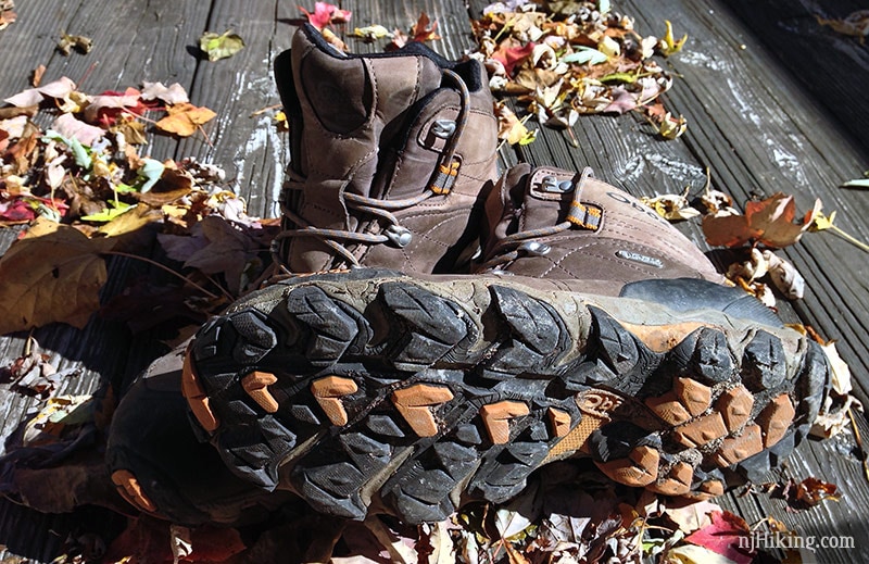 Men's mid-cut hiking boot on it's side, showing the tread on the bottom.