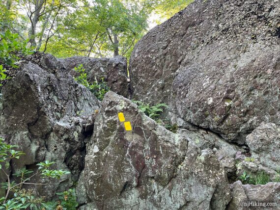 Yellow trail markers painted on a rock scramble.