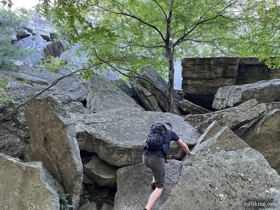 Hiker starting to climb up large rock slabs,